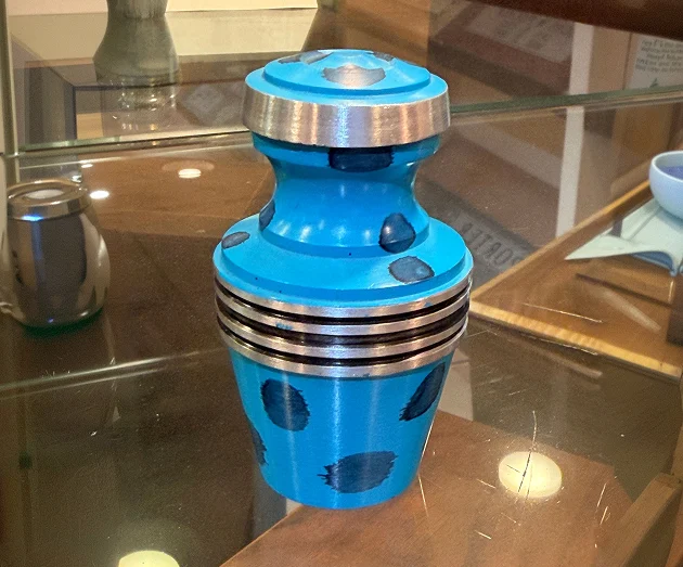 Bright turquoise blue metal cremation urn vase featuring silver bands and black polka dots