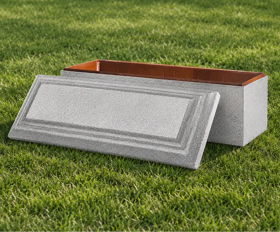 Lined concrete burial vault featuring a decorative textured lid and warm copper-colored inner lining, placed on green grass
