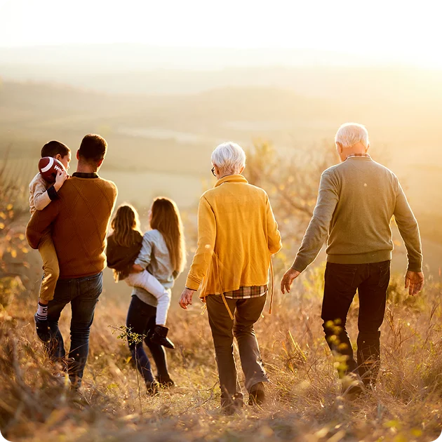 A heartwarming scene of a family, with seniors and children, walking through a warm, sun-drenched landscape, symbolizing the enduring family bonds and cherished legacies honored by the Dallas Casket Store.